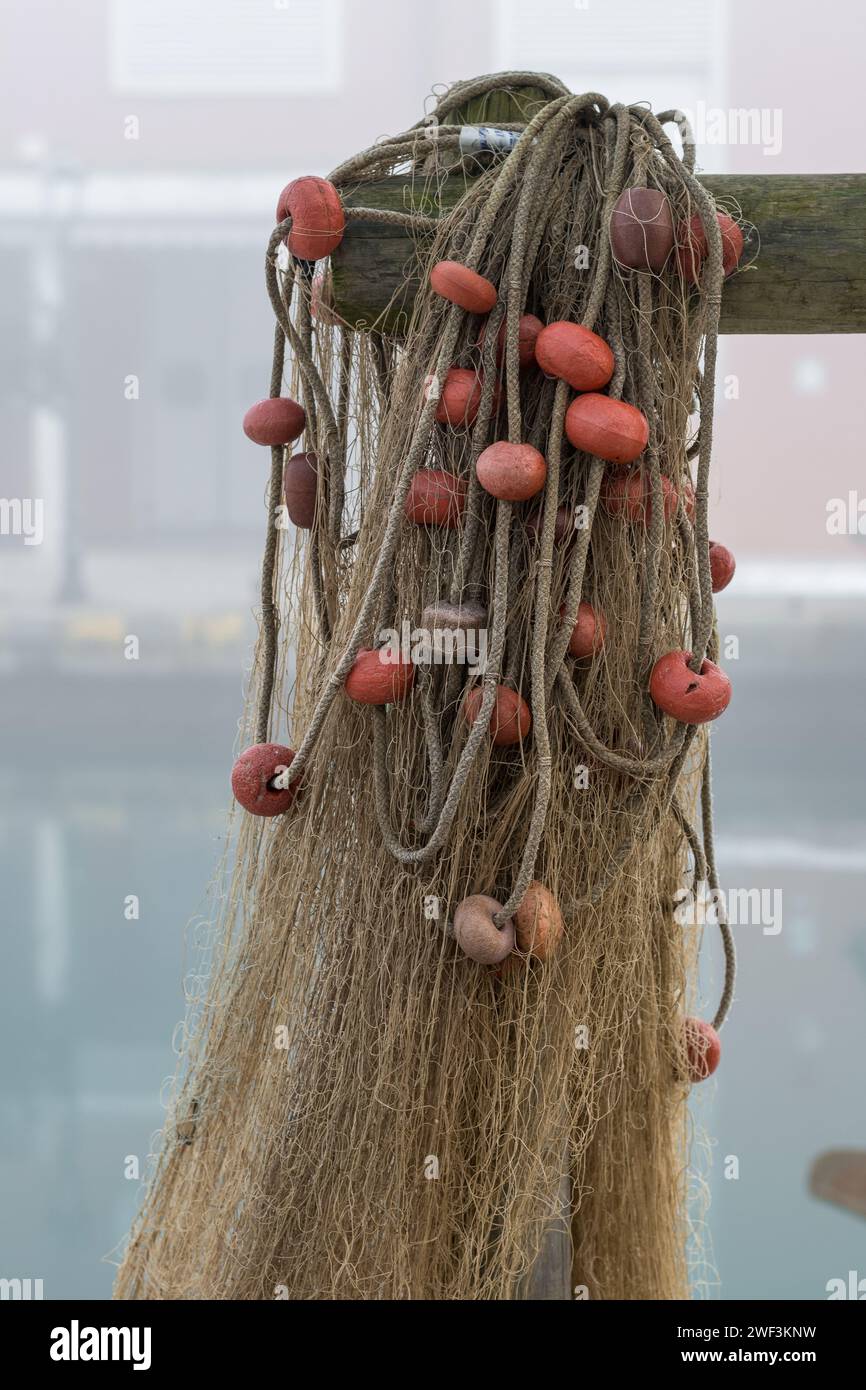 A series of fishing nets hung up near on the harbor near fishing boats after a fishing trip. Nets joined by plastic ropes and floats of various colors Stock Photo