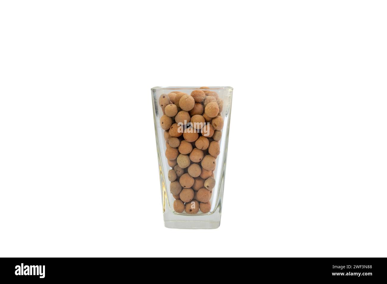 Leca clay balls artfully arranged in a transparent glass vase on white