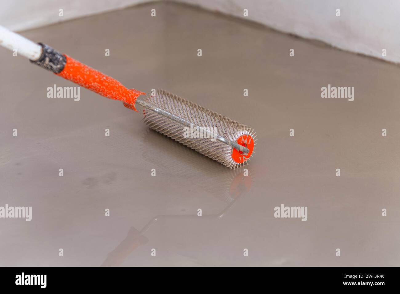 Needle roller for selfleveling floors. Leveling the floors with a cement mixture Stock Photo