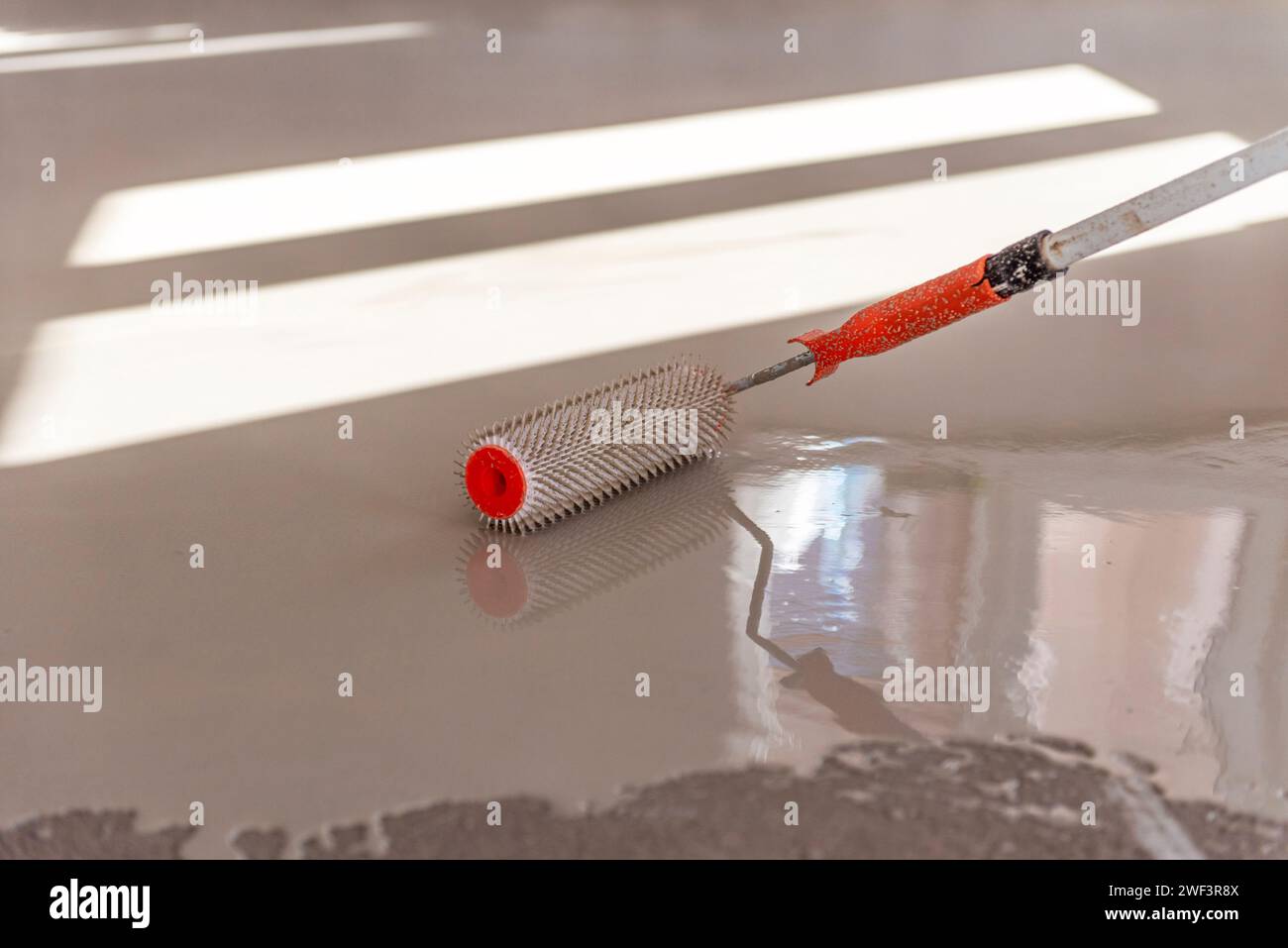 Needle roller for selfleveling floors. Leveling the floors with a cement mixture Stock Photo