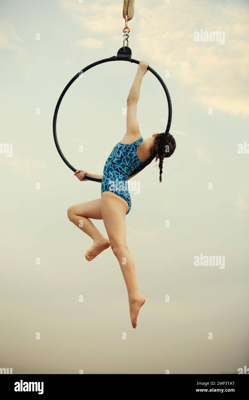 12 years old girl gymnast performing on aerial hoop outdoors Stock Photo