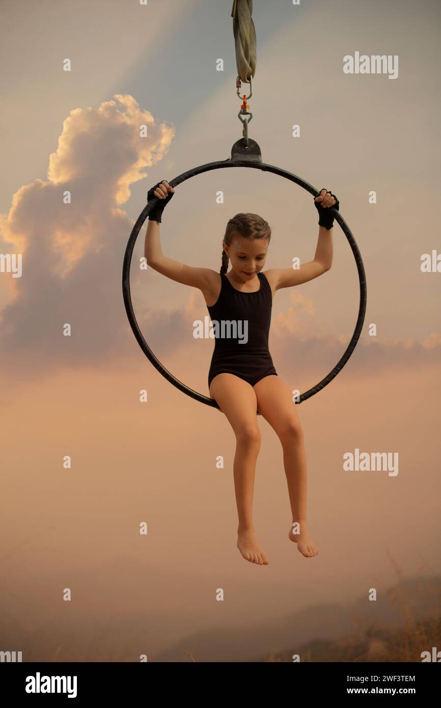 12 years old girl gymnast performing on aerial hoop outdoors Stock Photo