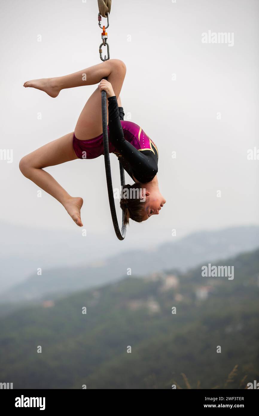 12 years old girl gymnast performing on aerial hoop outdoors Stock Photo