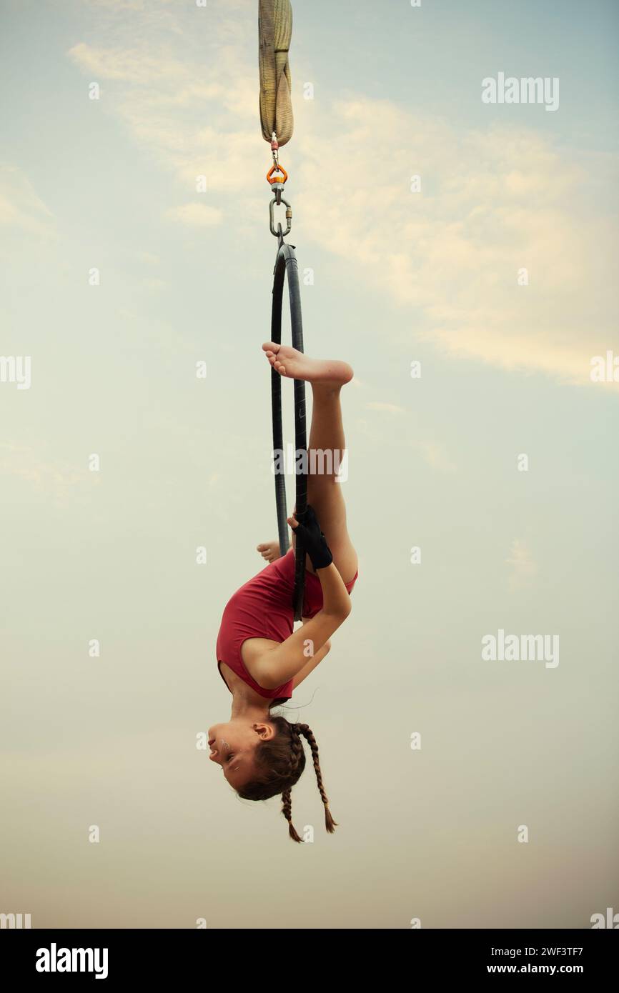 12 years old girl gymnast performing on aerial hoop outdoors Stock Photo