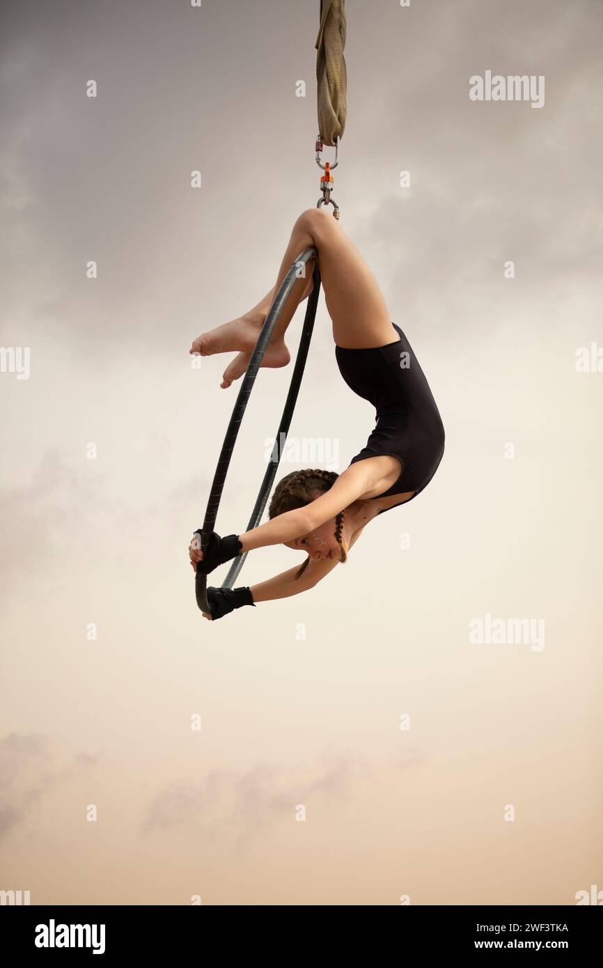 12 years old girl gymnast performing on aerial hoop outdoors Stock Photo