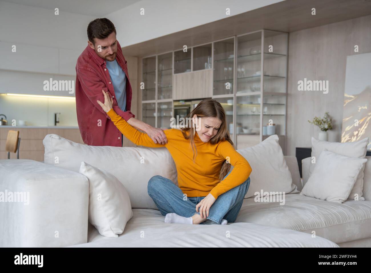 Jealous angry husband rudely touching wife hand. Crying wife suffering from domestic violence Stock Photo