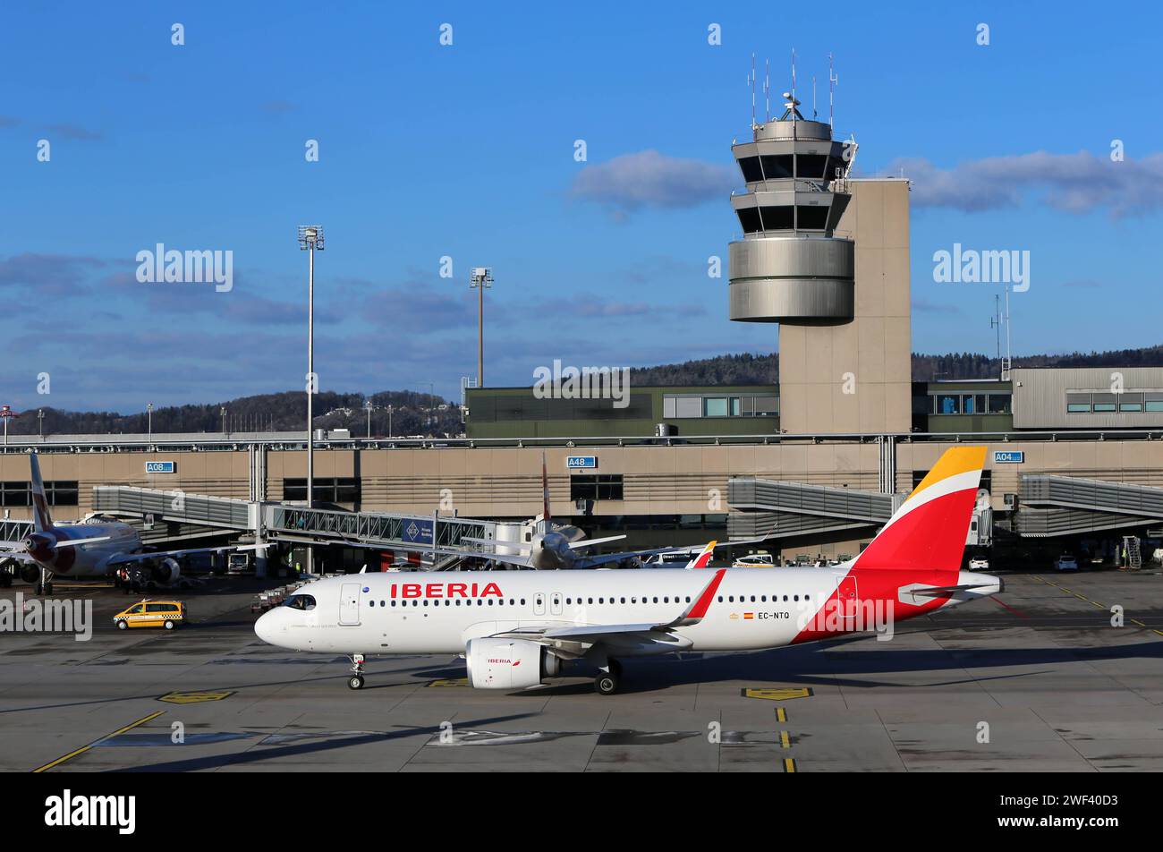 Flugbetrieb auf dem Flughafen Zürich-Kloten ZRH. Ein Passagierflugzeug der spanischen Fluggesellschaft Iberia vom Typ Airbus A320-251N mit der Kennung EX-NTQ auf dem Flughafen Zürich-Kloten ZRH. Im Hintergrund der Tower. *** Flight operations at Zurich Kloten Airport ZRH An Airbus A320 251N passenger aircraft of the Spanish airline Iberia with the registration EX NTQ at Zurich Kloten Airport ZRH The tower in the background Stock Photo