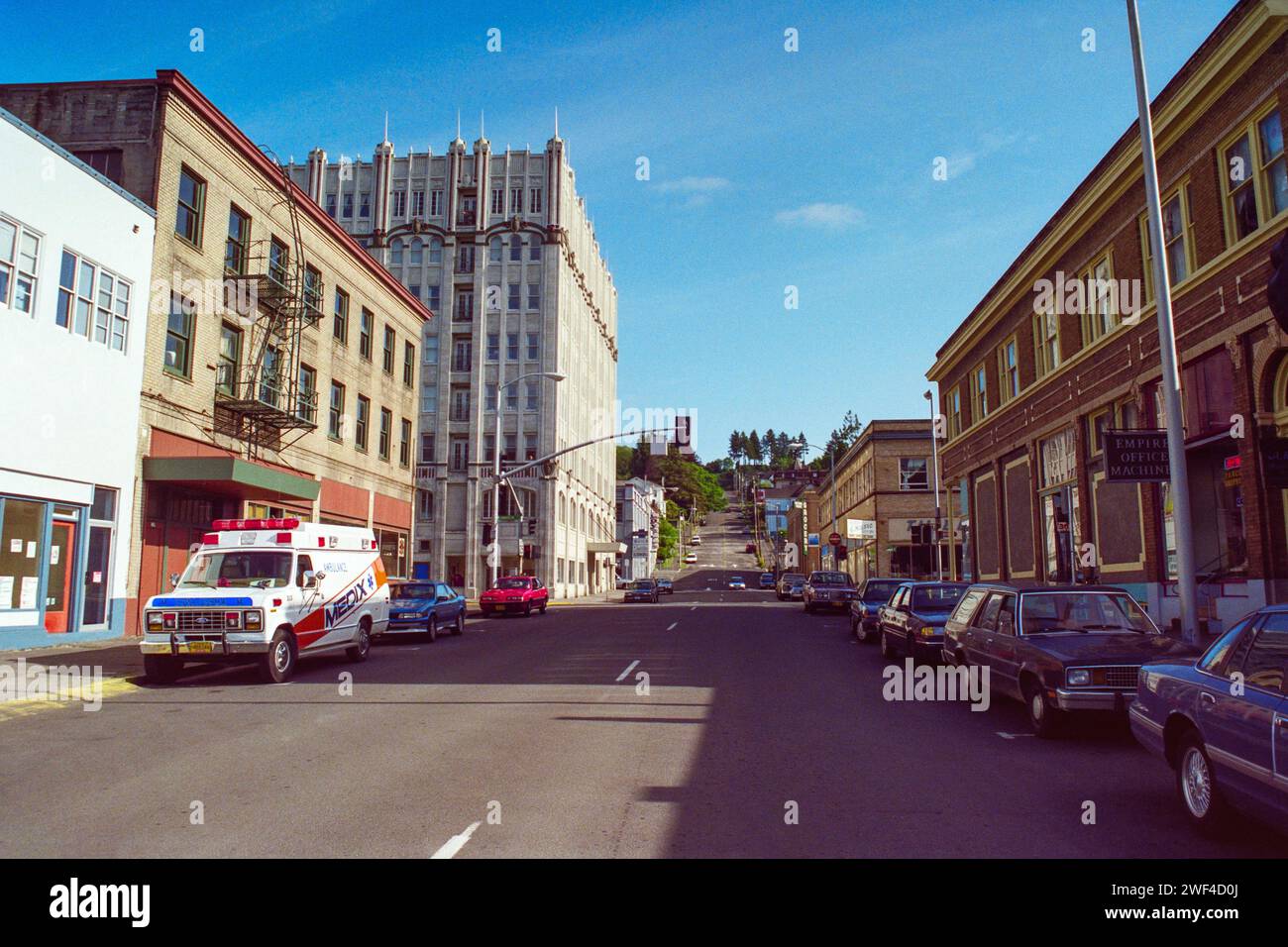 Astoria, Oregon, USA - May 12, 1992:  Grainy archival film photograph of Medix ambulance parked on Duane Street in historic downtown Astoria Oregon. Stock Photo