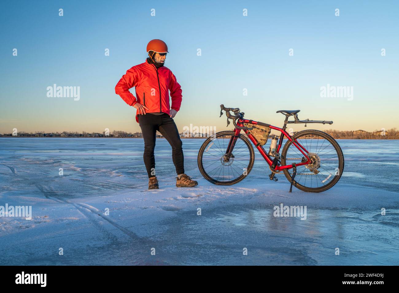 senior male cyclist with his gravel bike on a frozen lake in Colorado  - Boyd Lake State Park Stock Photo