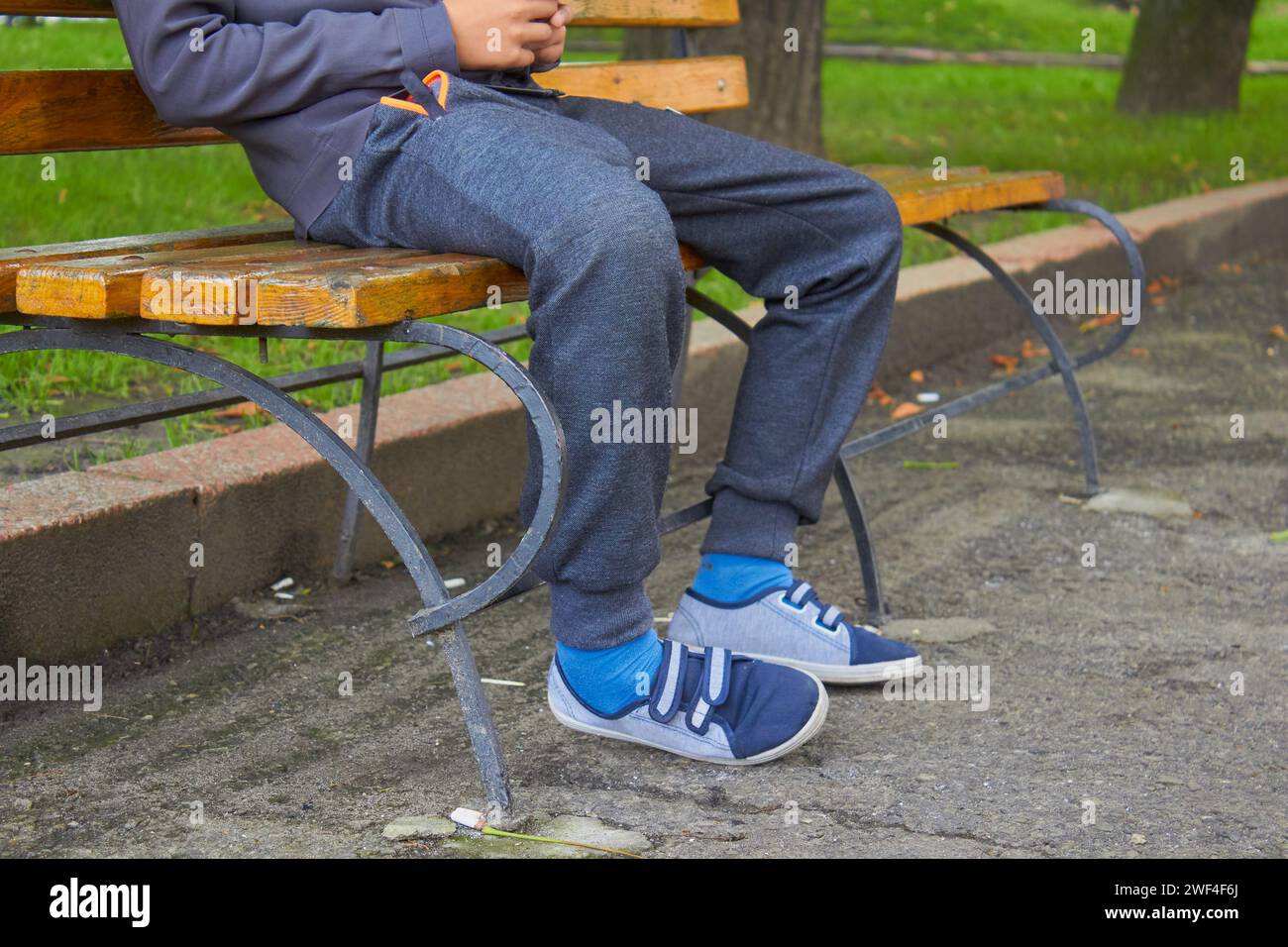 legs of a boy sitting on a park bench Stock Photo - Alamy