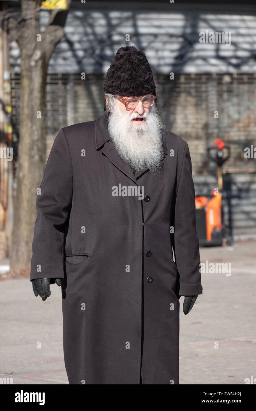 An older orthodox Jewish man walks on Lee Avenue wearing a karakul Russian fur hat. In Williamsburg, Brooklyn, New York City. Stock Photo
