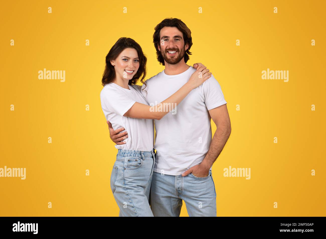 A happy couple in white t-shirts and blue jeans embrace each other with a smile Stock Photo