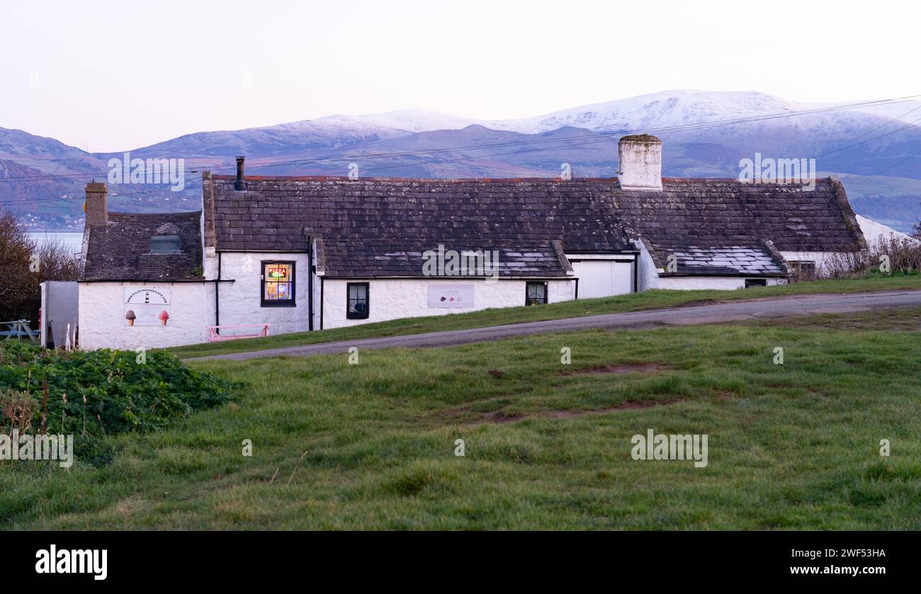 Pilot House Cafe, Black Point, Penmon, Anglesey, North Wales, in December 2024. The snow covered mountains of Snowdonia in the distance. Stock Photo