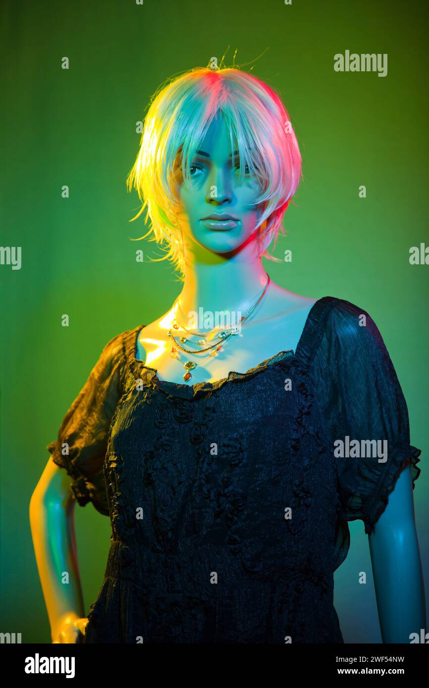 Plastic woman mannequin wearing short white hair posing in a four (4) colors studio lighting red blue yellow green effect Stock Photo