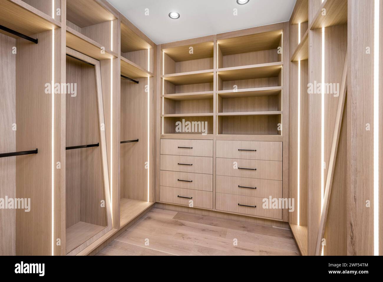 A spacious walk-in closet with stylish wooden shelves, drawers, and open shelving for organization Stock Photo