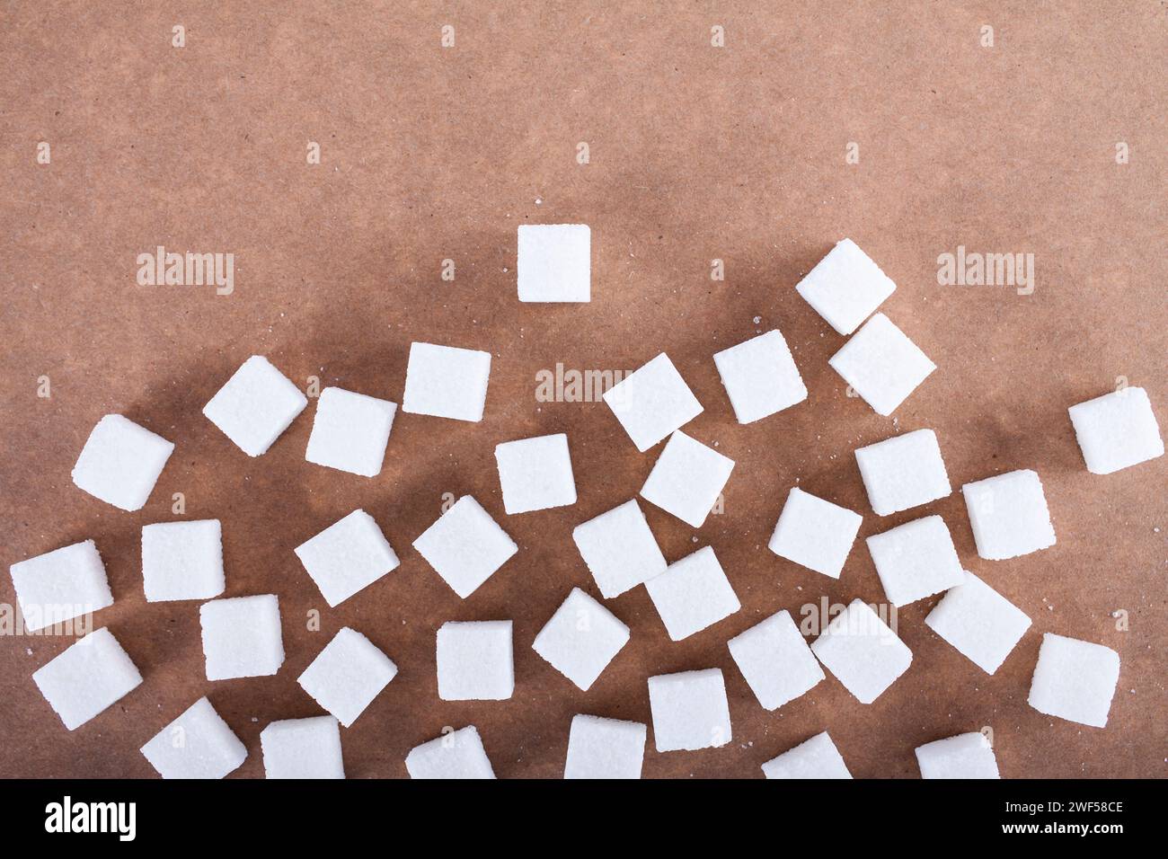 White sugar cubes on brown background Stock Photo