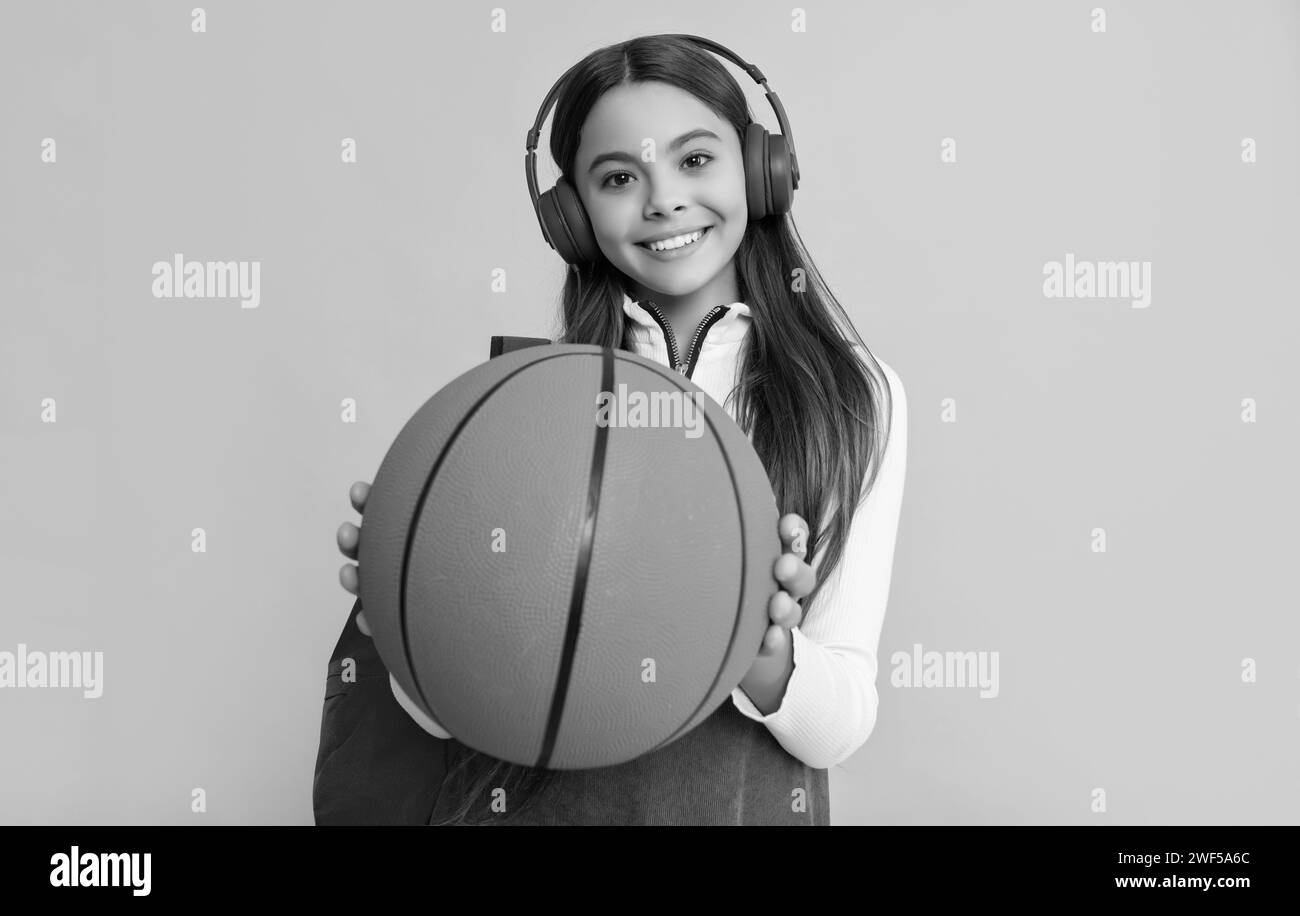 smiling child in headphones with school backpack and basketball ball. selective focus Stock Photo