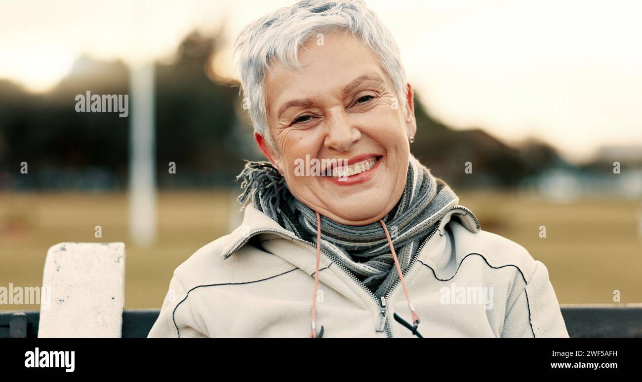 Face, senior woman and funny on park bench on vacation, holiday or travel in winter. Portrait, happy and elderly person in nature, outdoor or garden Stock Photo