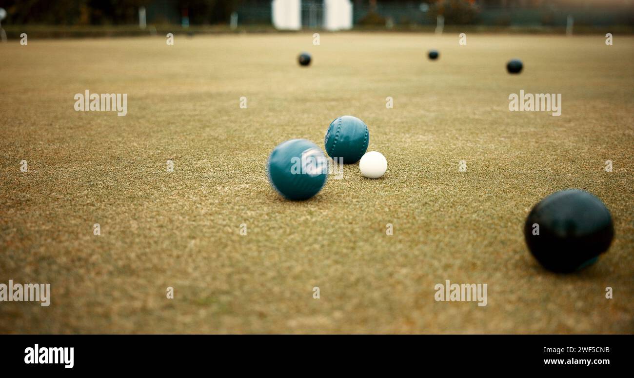 Green, balls and lawn bowling game on grass, field or pitch in a match or competition of outdoor bowls. Ball, moving and sport tournament at a bowlers Stock Photo