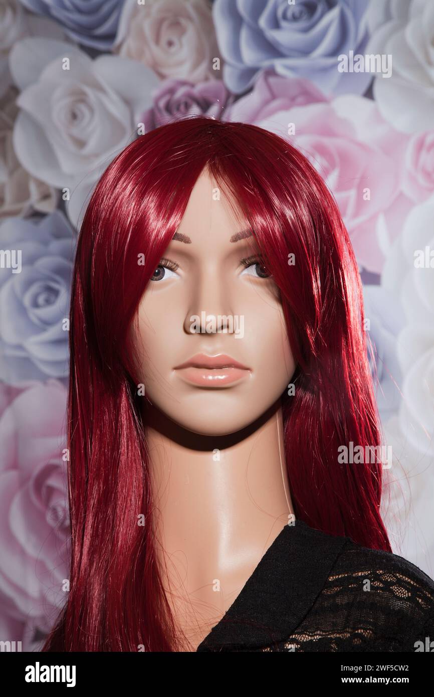 Plastic woman mannequin with long straigt red hair posing in front of a