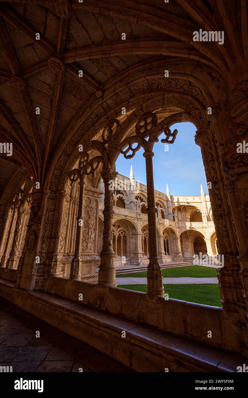 Empty inner courtyard viewed through an ornate window at the historic Mosteiro dos Jeronimos (Jeronimos Monastery) in Belem, Lisbon, Portugal. Stock Photo