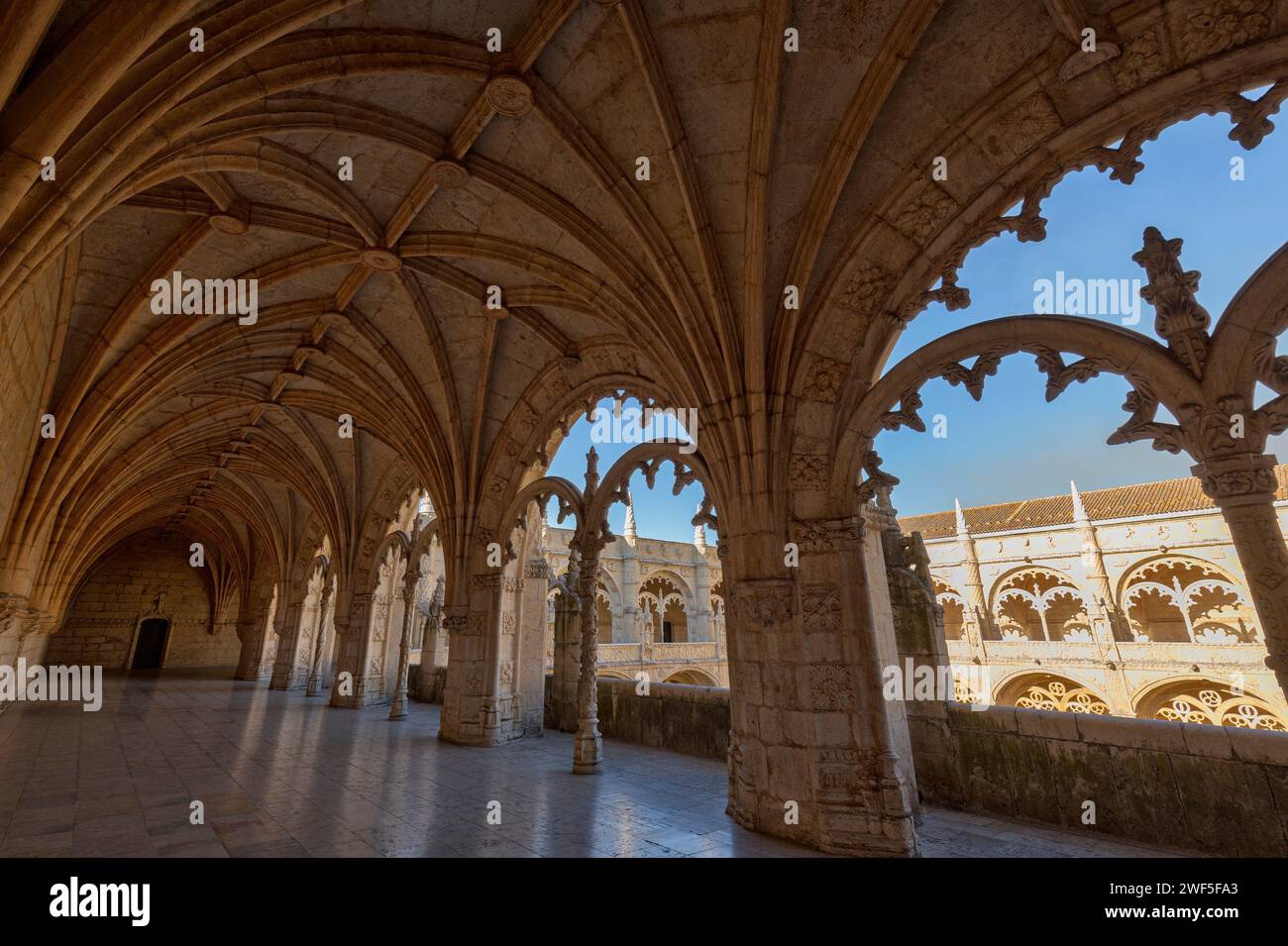 Empty inner courtyard viewed through an ornate window at the historic Mosteiro dos Jeronimos (Jeronimos Monastery) in Belem, Lisbon, Portugal. Stock Photo