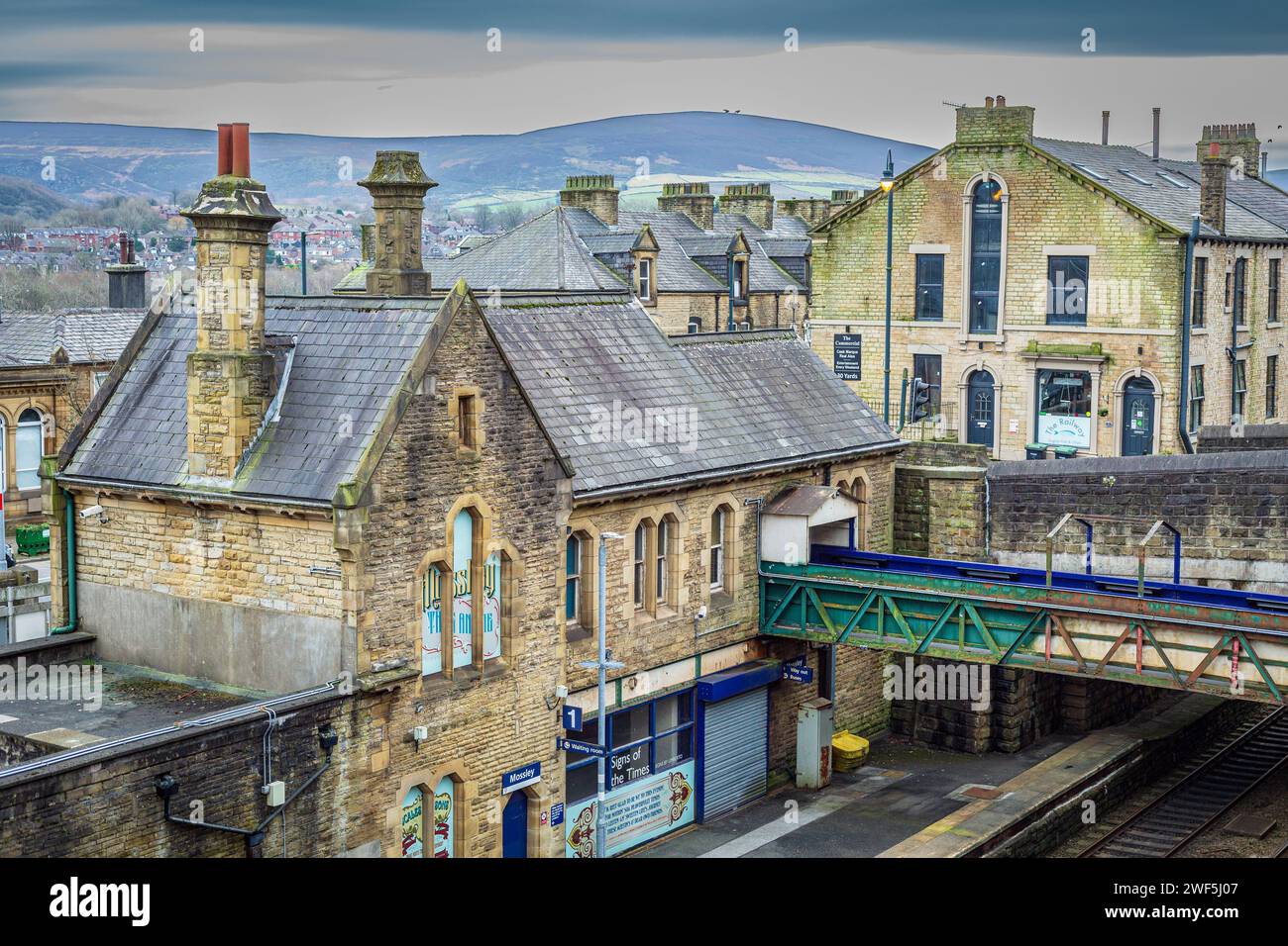 Stone buildings by Mossley railway station with hills in the background