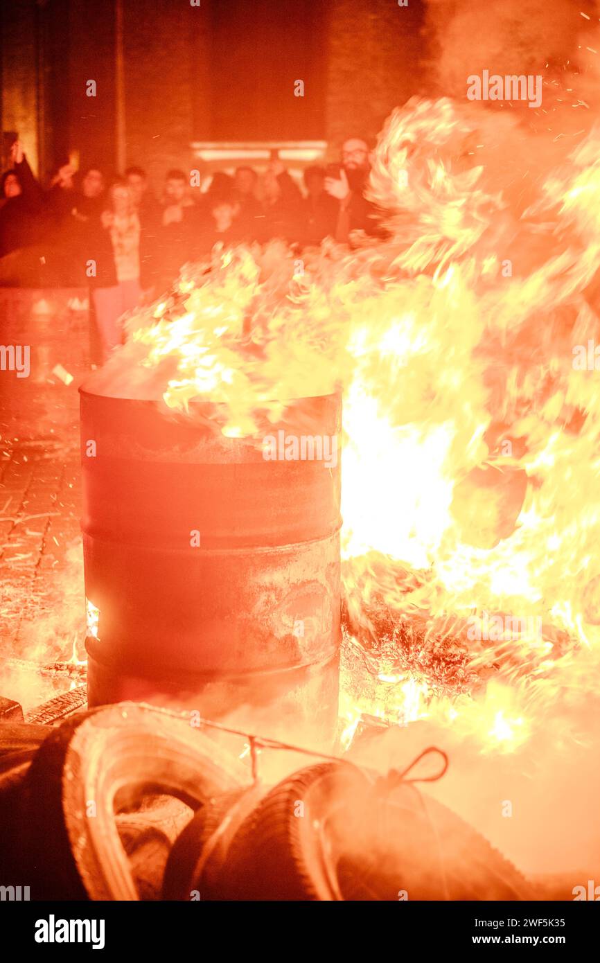 Turnhout, Antwerp, Belgium, 28th of January, 2024, This photograph captures an intense moment at the Turnhout farmers' protest against the Nitrogen Agreement in Belgium, focusing on a bonfire blazing in a barrel. The flames leap energetically, casting a warm glow that illuminates the faces of the onlookers, who watch with a mix of concern and determination. The fire becomes the central symbol of the protest, a beacon for the farmers' fiery resolve against the contentious policy. The crowd in the background is partially blurred, emphasizing the fire's prominence in the shot. Flames of Defiance: Stock Photo