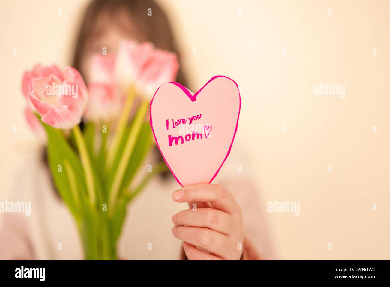 Mothers Day. girl with tulips and heart card.Pink heart card and pink tulips close-up in the hands of a girl.moms day  Stock Photo