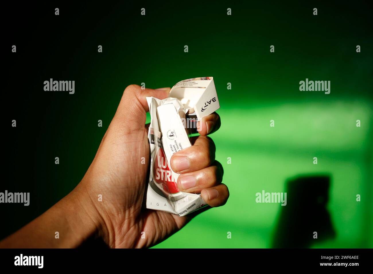 Close up of a hand squeezing an empty pack of Lucky Strike cigarettes Stock Photo