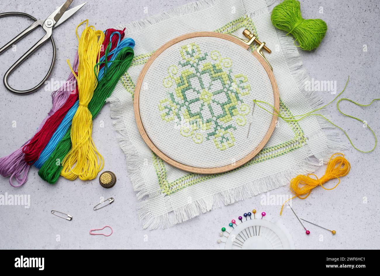 Embroidery with colored threads and various sewing accessories on the table Stock Photo