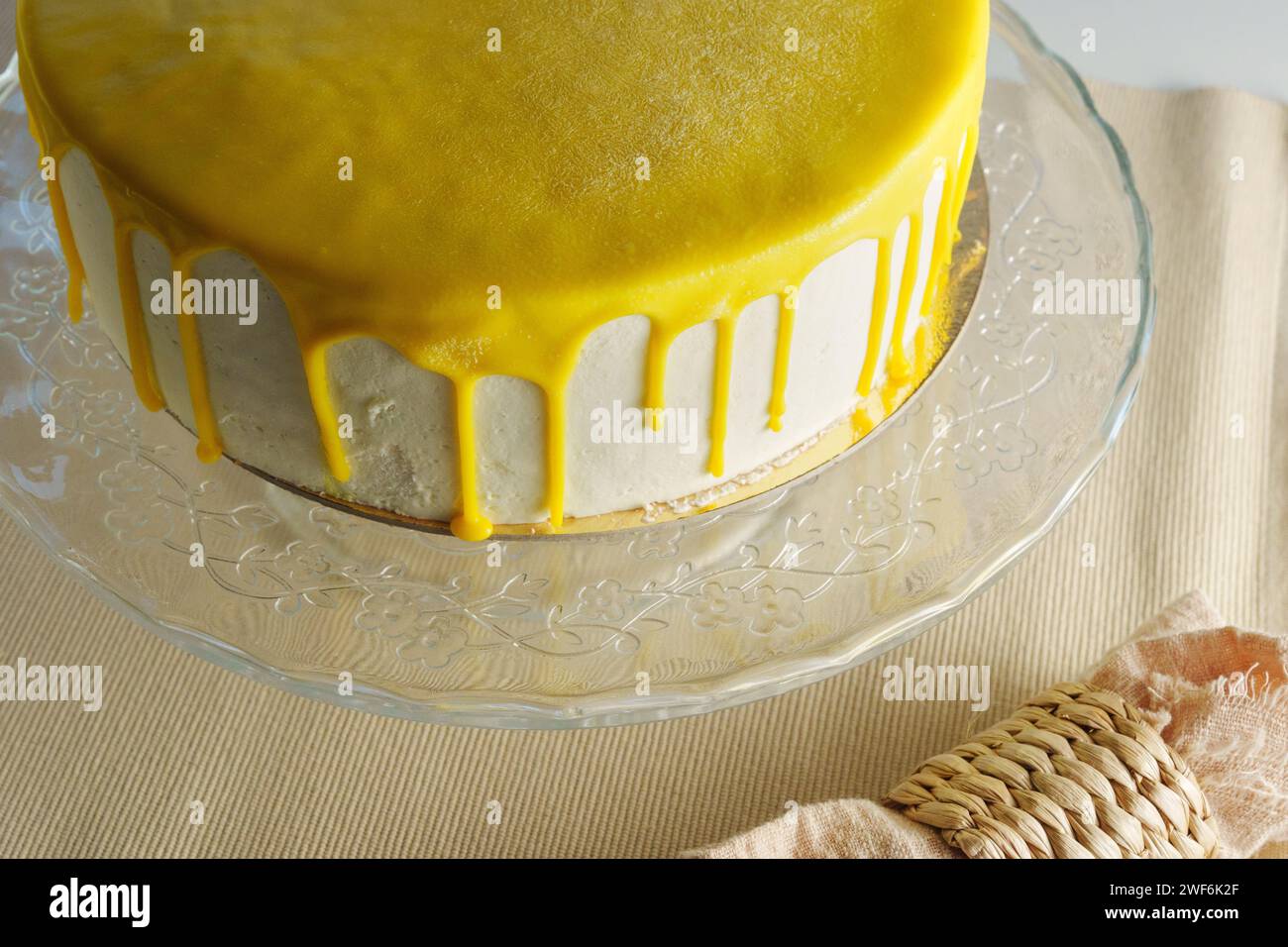Cake sits elegantly on a glass stand, adorned with a glistening lemon glaze Stock Photo