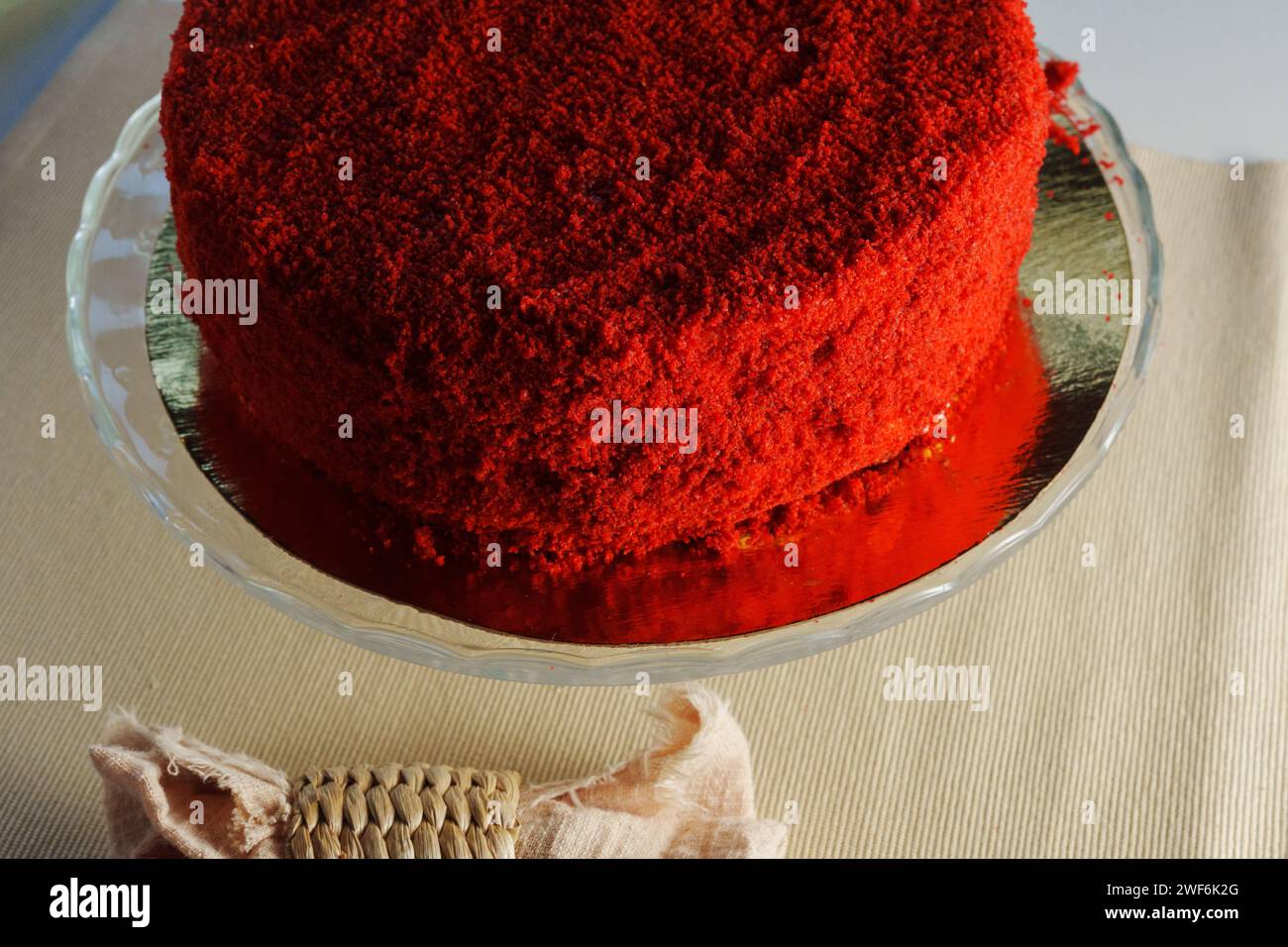 Red velvet cake takes center stage, served on a transparent glass dish Stock Photo