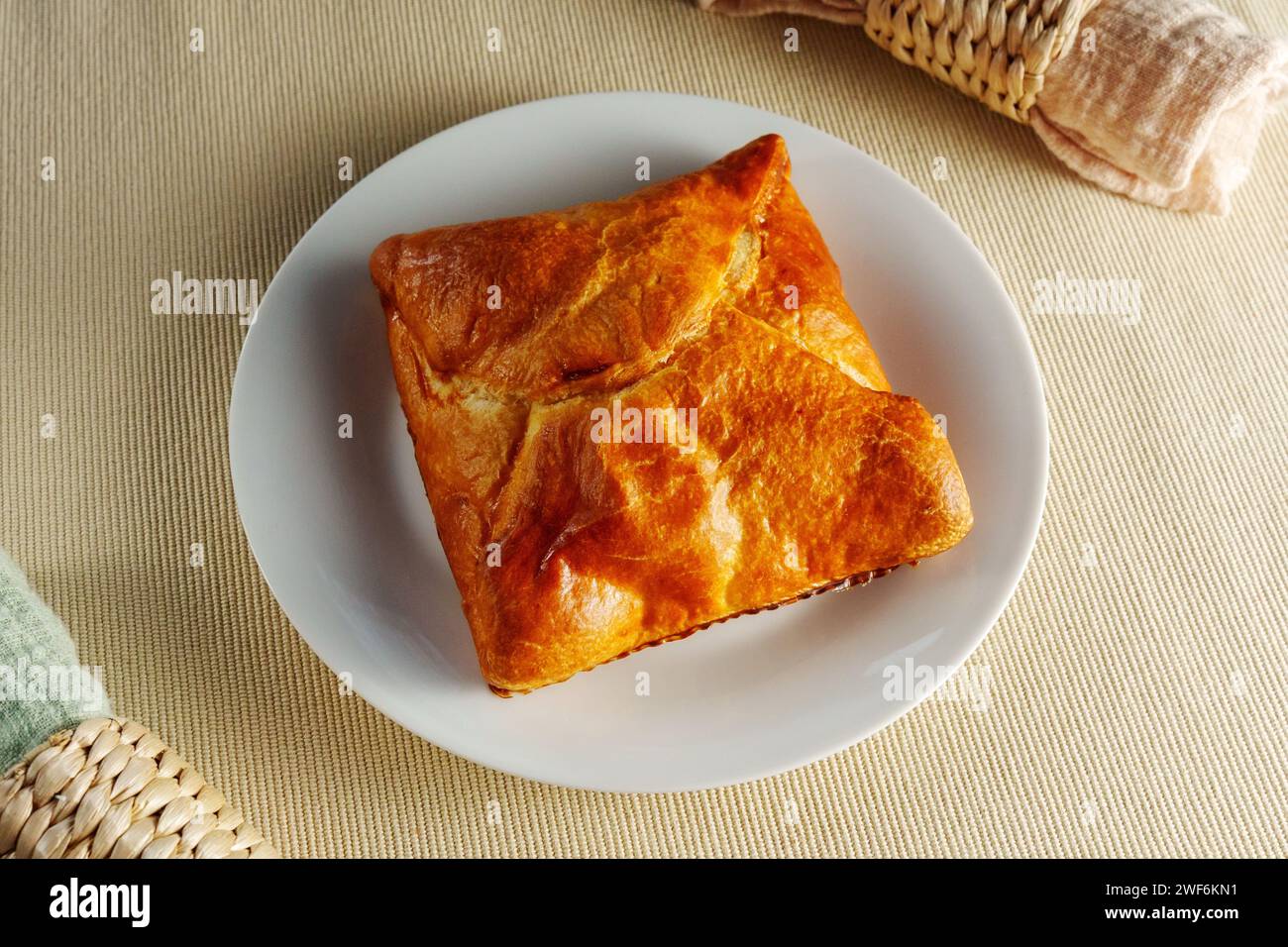 A visually stunning composition featuring a perfectly baked puff pastry adorning a pristine white plate. Stock Photo