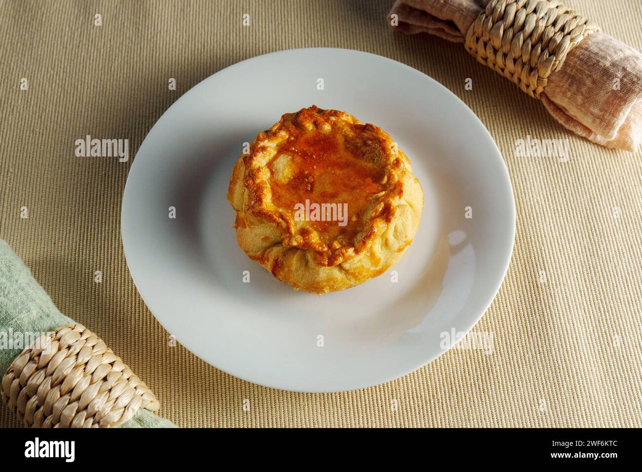 A Flaky Delight: A White Plate Showcasing a Delectable Pastry on a Mesmerizing Table Stock Photo