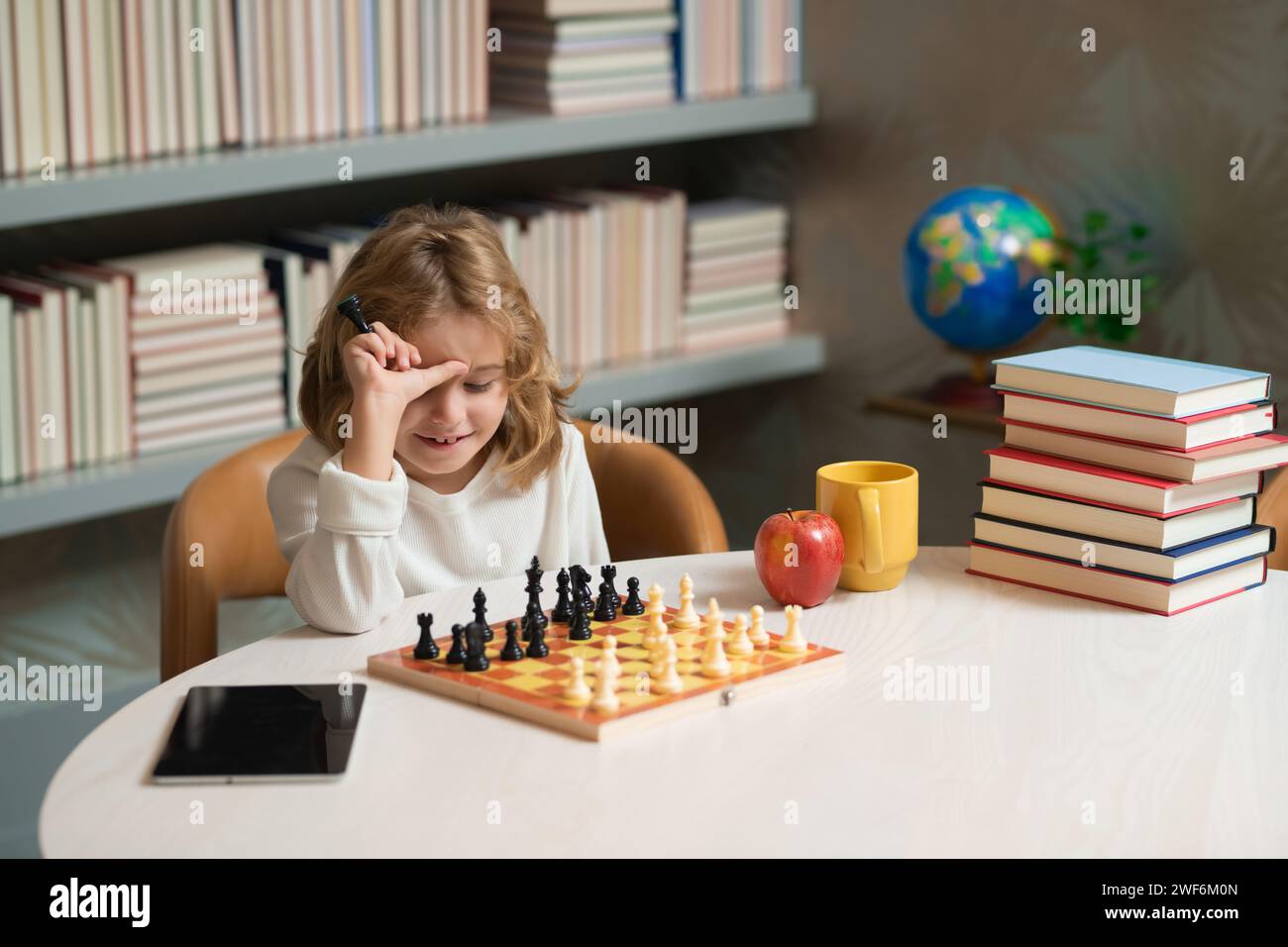 Kid playing chess in the room. Early development. Boy thinking about chess. The concept of learning and growing children. Chess, success and winning Stock Photo