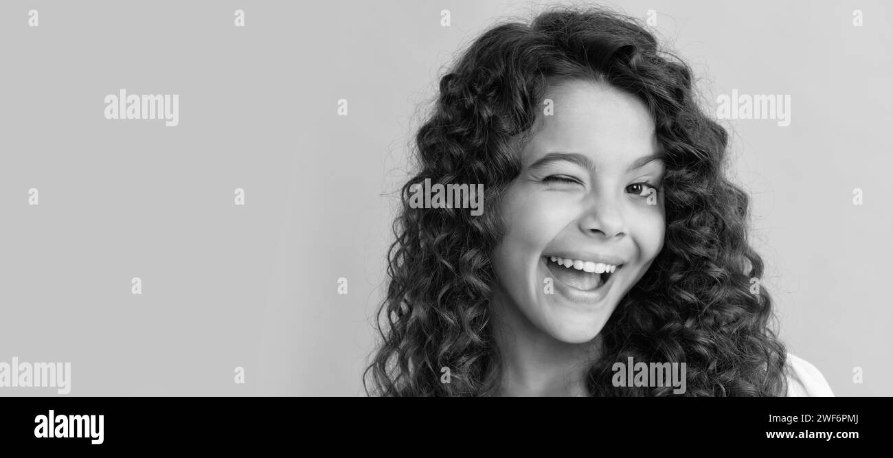 happy winking teen girl with long curly hair and perfect skin, frizzy. Child face, horizontal poster, teenager girl isolated portrait, banner with cop Stock Photo