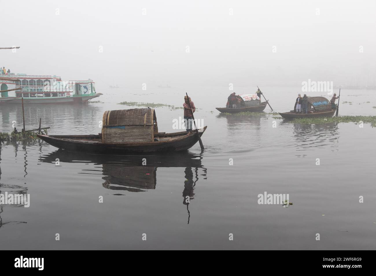 Narayanganj, Dhaka, Bangladesh. 29th Jan, 2024. People cross Shitalakhya River on wooden boats to reach their workplace during a foggy winter morning in Narayanganj, Bangladesh. This river is used as a route into the heavily populated urban area by millions of workers every day. The wooden vessels transport people across the Shitalakhya river, which flows on the outskirts of the city of Narayanganj. (Credit Image: © Joy Saha/ZUMA Press Wire) EDITORIAL USAGE ONLY! Not for Commercial USAGE! Credit: ZUMA Press, Inc./Alamy Live News Stock Photo