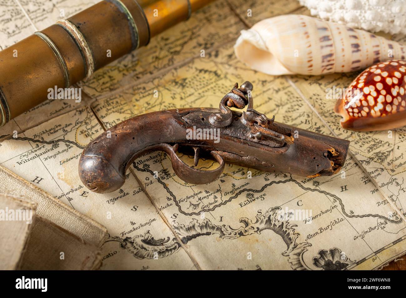 Antique pistol on a map with a copper spyglass and some sea shells Stock Photo