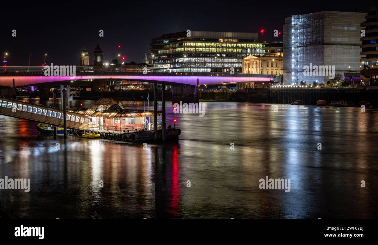 London. UK-01.27.2024. A night time view of London Bridge with colourful reflections on the water of the Thames River. Stock Photo