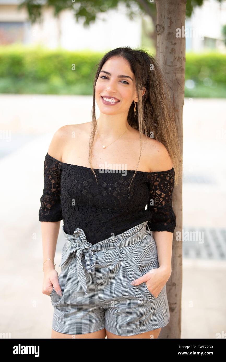 Beautiful young woman looking at camera smiling outdoors Stock Photo