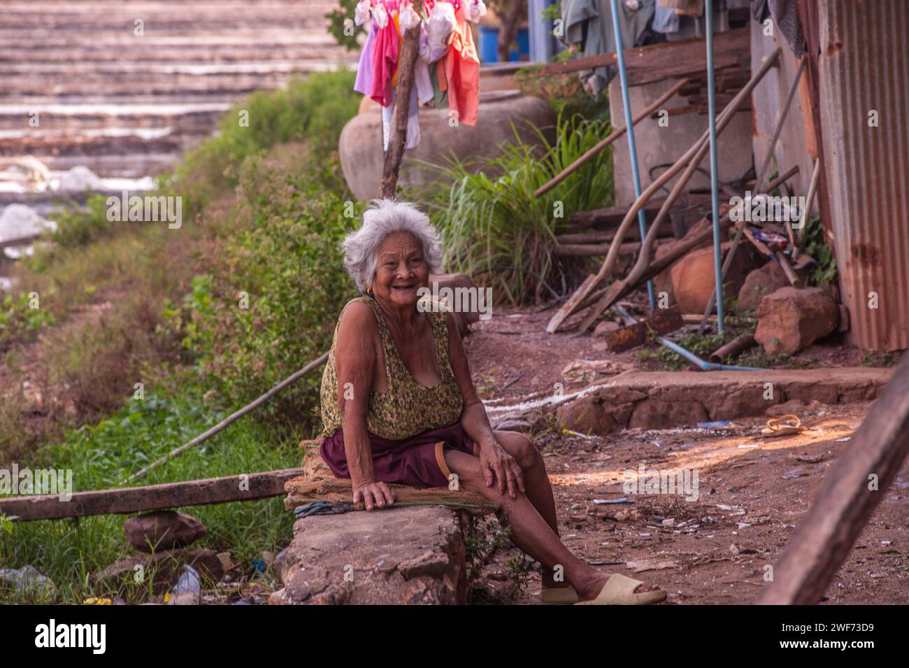 An old Cambodian woman sits near the salt fields. Fish Island, Kampot Province, Cambodia. credit: Kraig Lieb Stock Photo