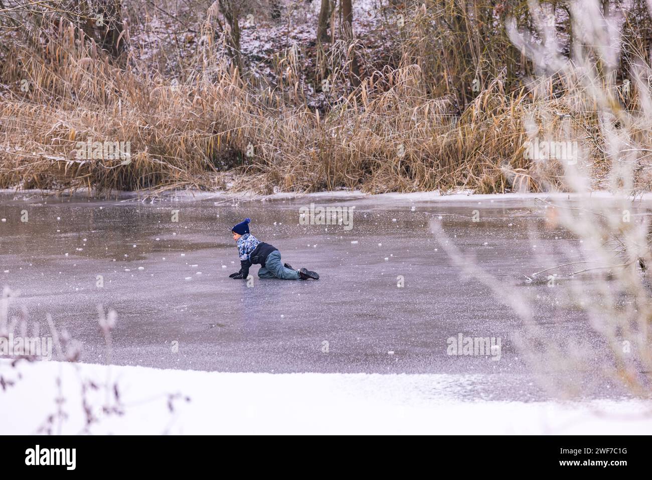 A child on a frozen lake in winter is risky and life-threatening, Riedstadt, December 18th, 2022 Stock Photo
