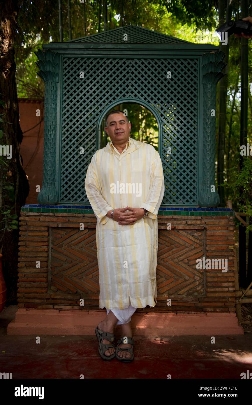 A man wearing traditional Middle eastern dress stands in a Moroccan garden. Stock Photo