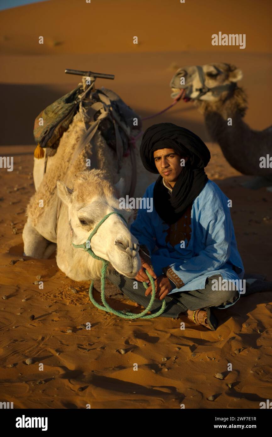 Camel Guide Block A camel guide sits with his animal in the sand dunes at sunrise Stock ...