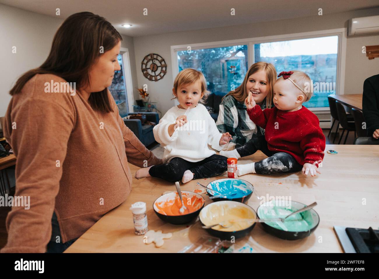 Moms and daughters gather, ready to frost cookies, joy Stock Photo