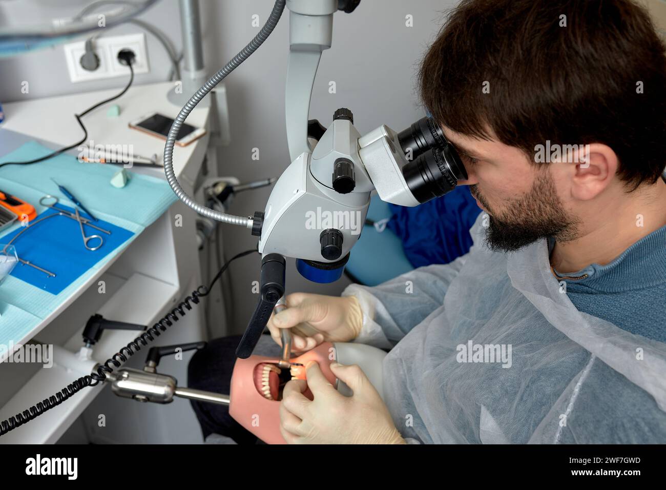 Male dentist is learning to treat teeth on human head mannequin using