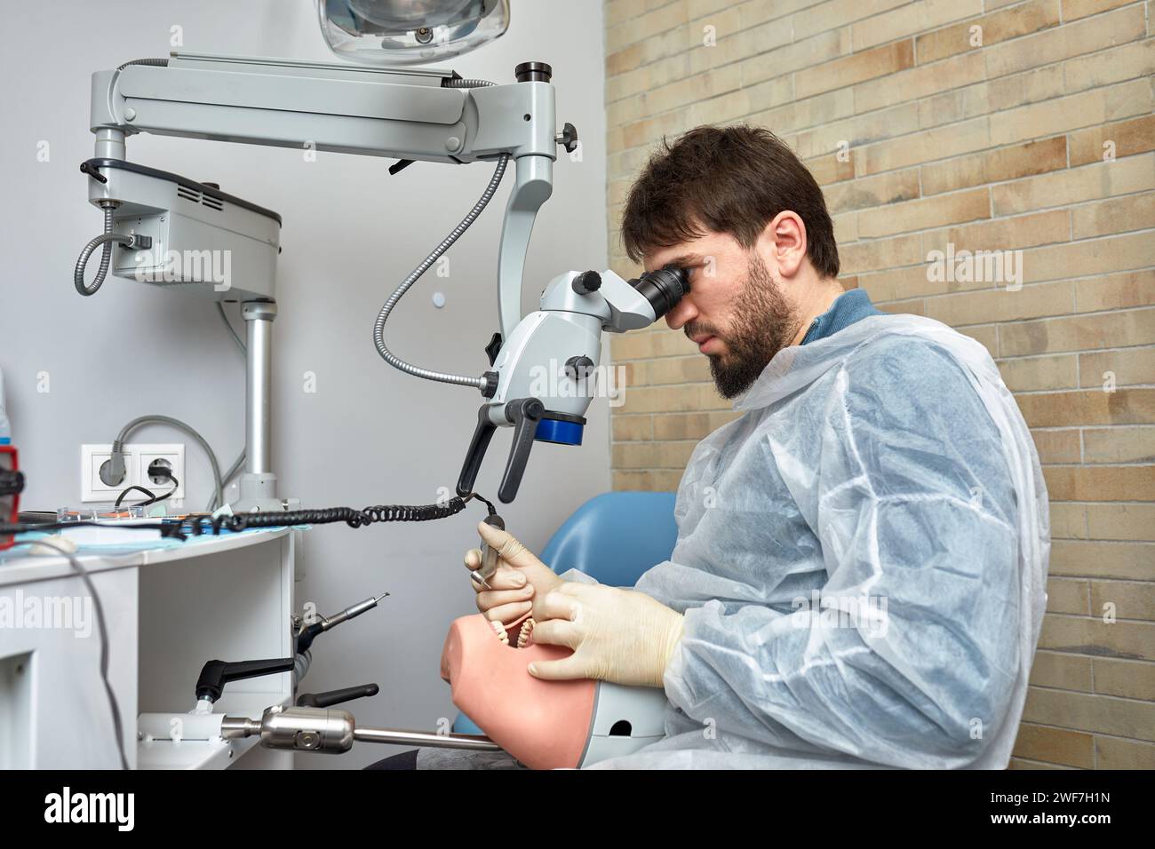 Male dentist is learning to treat teeth on human head mannequin using