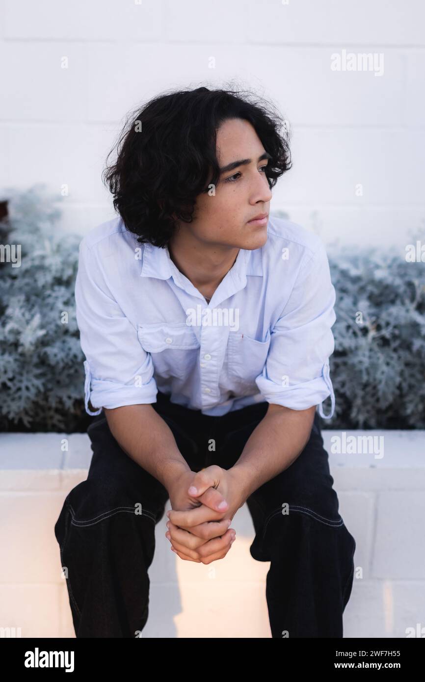 Young man sitting staring and thinking Stock Photo - Alamy