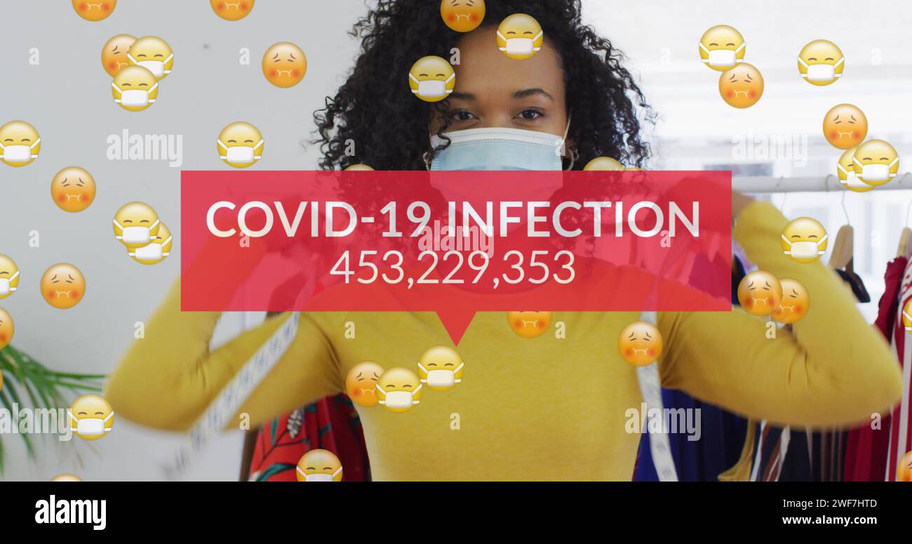 Image of words covid-19 infection and emoji floating with woman wearing face mask Stock Photo